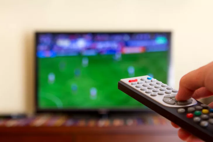 Barbat urmarind un meci de fotbal la tv