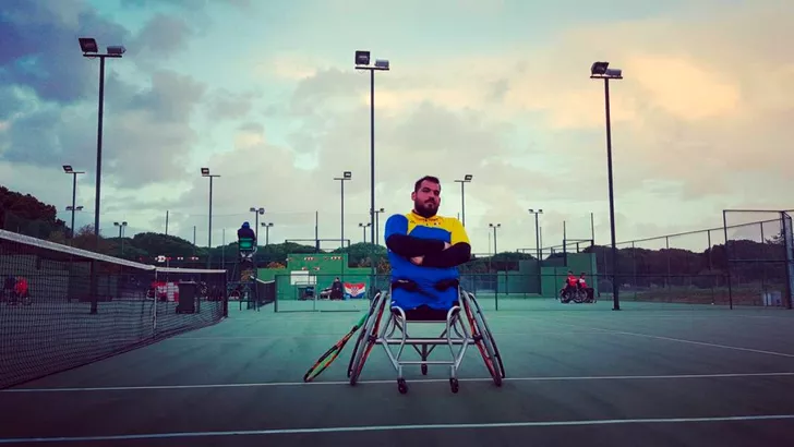 Ionuţ Filişan joacă tenis în scaun cu rotile. 